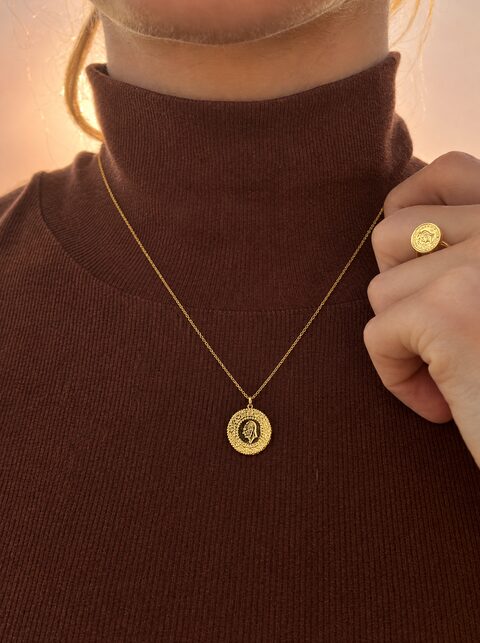 Kette mit Goldmünze und Münzring zu einem braunen Rollkragenpullover